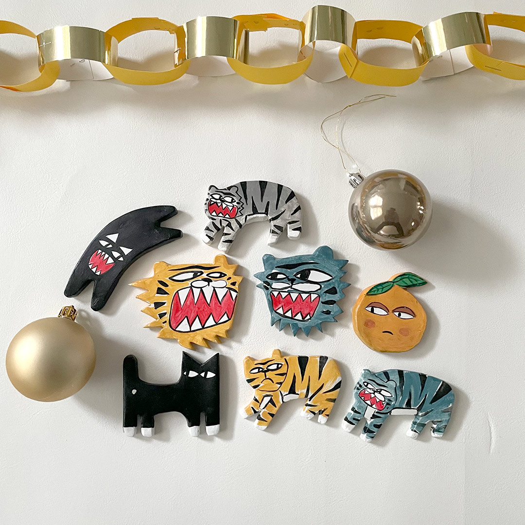 a selection of clay cat magnets including black cats and colourful tigers and an orange