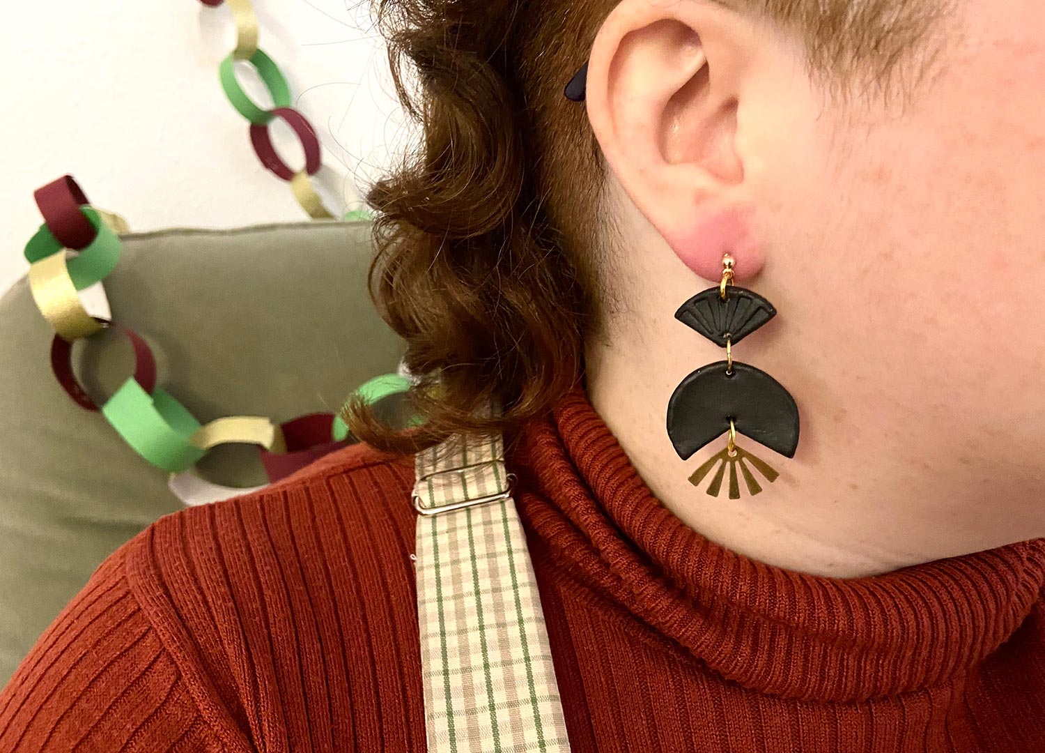 a model wears a black geometric earring with a metallic fan 