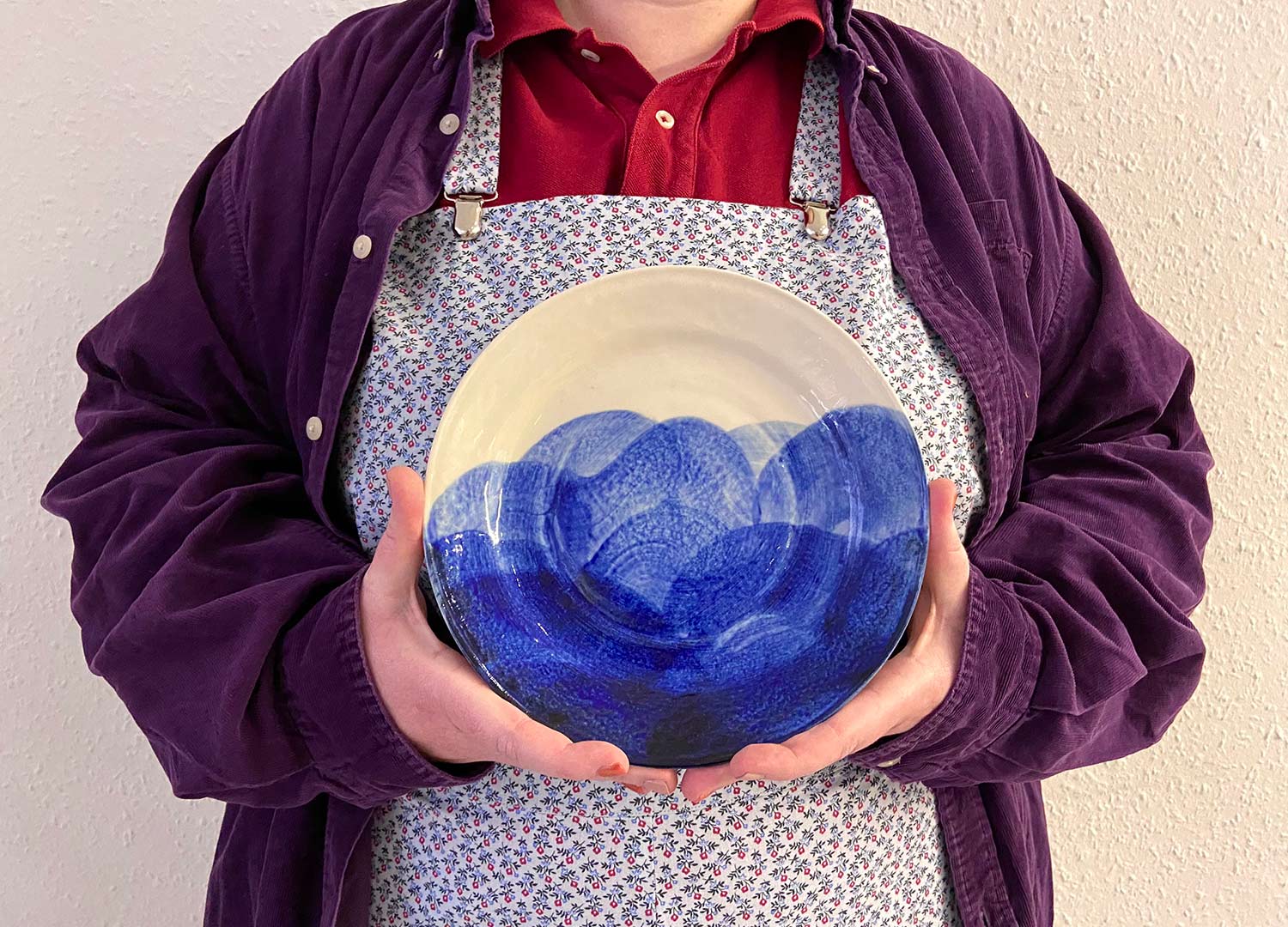 a model holds a blue and cream hand painted slip cast plate