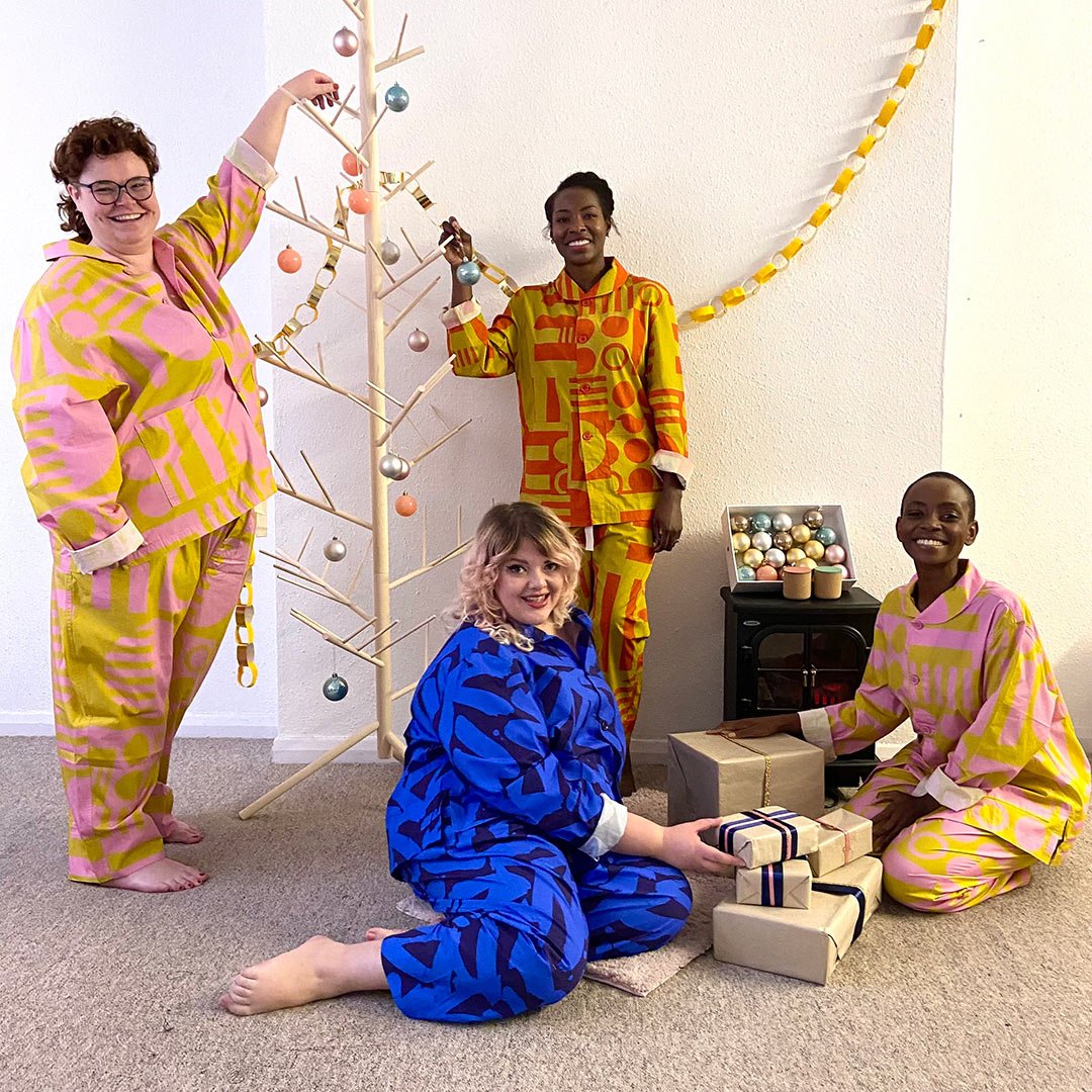 four models wearing colourful pyjamas are smiling looking at the camera 