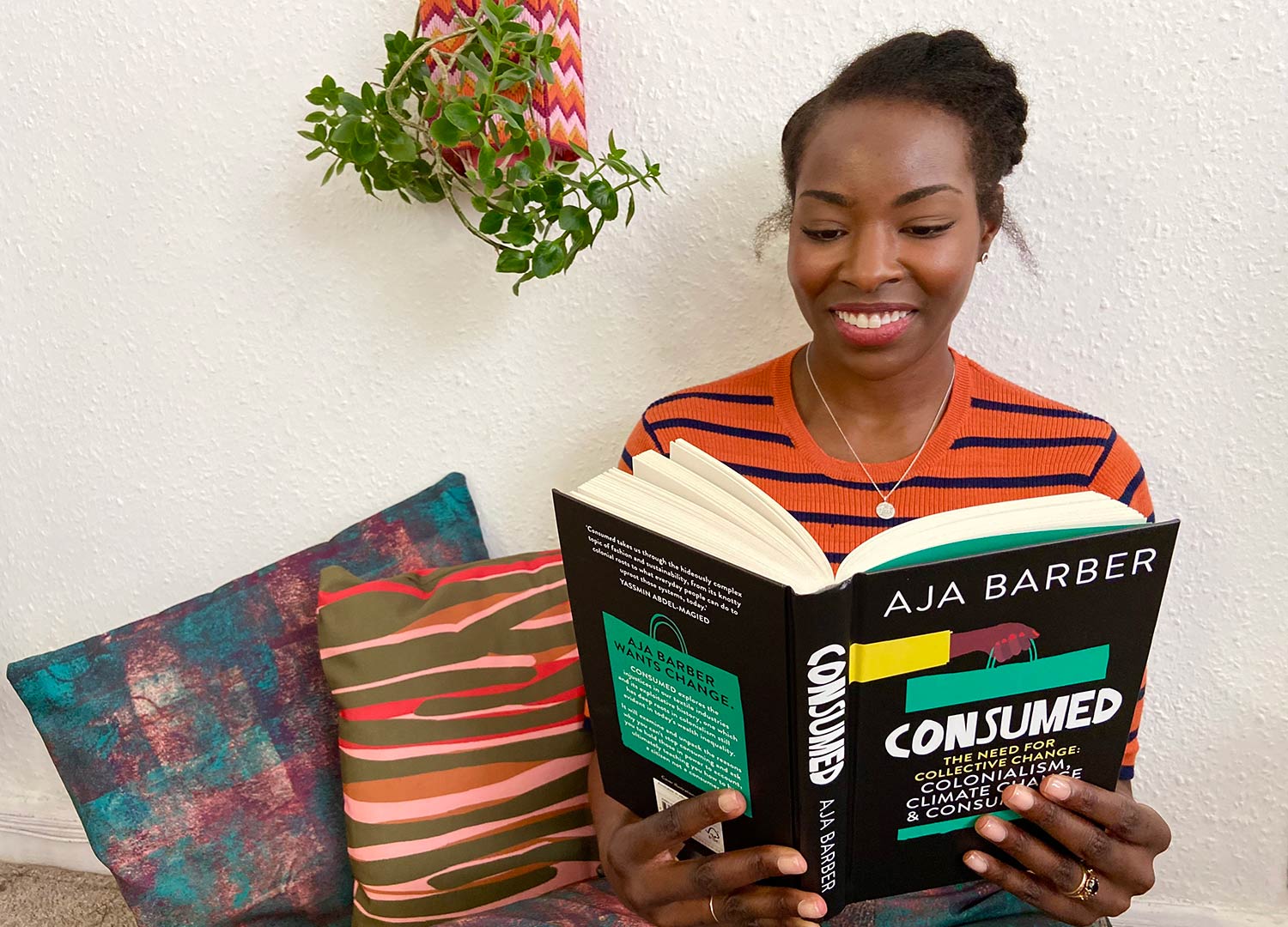 a model holds Aja Barber's book consumed and there are pillows behind her