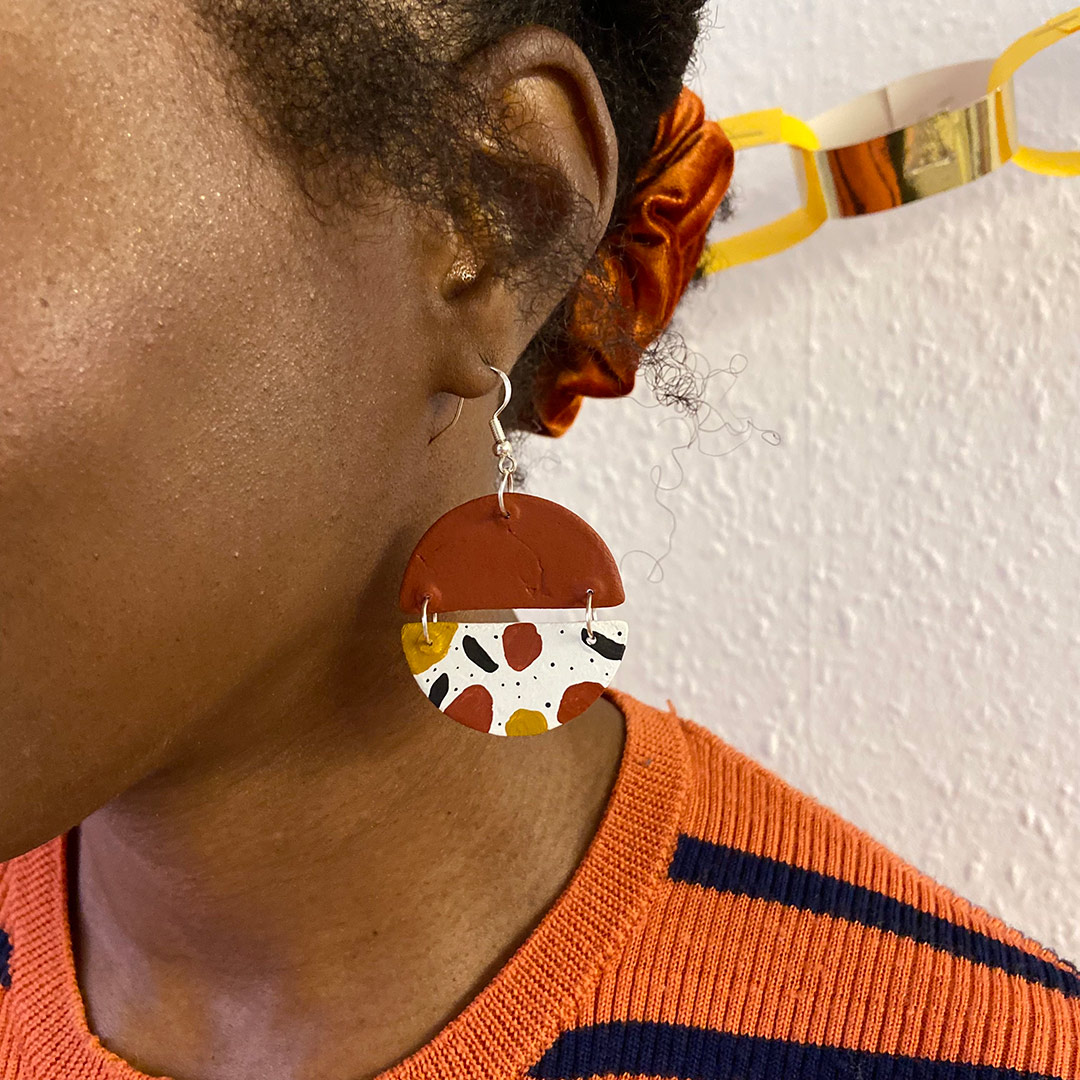 a model wears a brown circular geometric earring