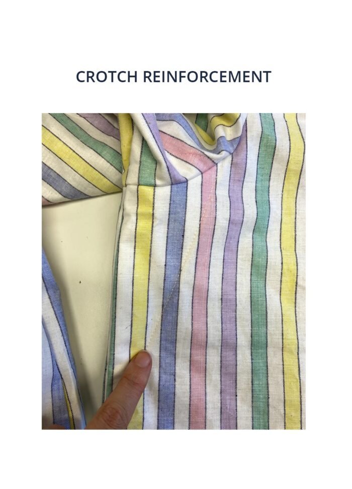 Image of our trousers with crotch reinforcement - image shows a finger pointing to a simple stitch on the garment which shows how the crotch reinforcement looks from the outside.