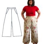 Our model Fenia is stood with their hands in their pockets of their floral wide leg trousers. Fenia is wearing a bright red t-shirt and is barefoot.