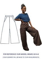 Model Michiel is wearing a UK Size 6-8 pair of wide leg trousers in an amazing brown and blue checked fabric. Michele is looking at the camera smiling with a hand on their hip and their leg propped up on a stair.